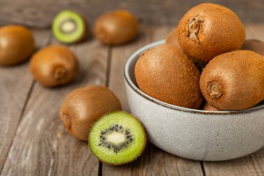 Ahşap arka planda Kivi. Masada tam meyve ve dilimler halinde yeşil kivi var. Taze sulu kivi. Tropik meyve. Organik meyve. Sağlıklı beslenme. Mesaj için yer var. Boşluğu kopyala