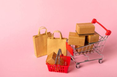 Çevrimiçi alışveriş kavramı. Karton kutu ve parlak renkli bir arka planda tramvayda alışveriş poşetleri. Alışveriş sepeti. İnternetten bilgisayar, tablet, telefon ve kredi kartı kullanarak alışveriş. Eve teslim.