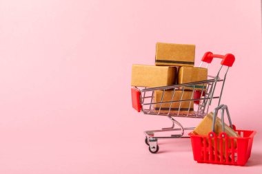 Çevrimiçi alışveriş kavramı. Karton kutu ve parlak renkli bir arka planda tramvayda alışveriş poşetleri. Alışveriş sepeti. İnternetten bilgisayar, tablet, telefon ve kredi kartı kullanarak alışveriş. Eve teslim.