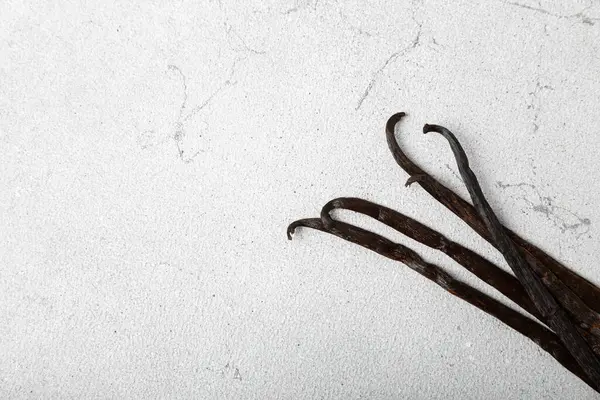 Dokulu bir arka planda vanilya kabukları. Vanilya çiçekleri ve tohumlar. Vanilyalı fasulye. Hamur işleri ve tatlılar için baharatlı baharat. Baharat. Mesaj için yer var. Boşluğu Kopyala