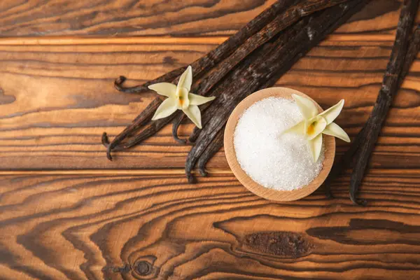 Aromatik vanilya şekeri. Vanilya kabukları. Vanilya çubukları, esmer ve beyaz şeker dokulu arka planda bir kasede. Vanilya çiçekleri, baharatlar ve tatlı ve pişirme için bitkiler. Mesaj için yer var. Boşluğu kopyala