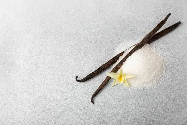 Aromatik vanilya şekeri. Vanilya kabukları. Vanilya çubukları, esmer ve beyaz şeker dokulu arka planda bir kasede. Vanilya çiçekleri, baharatlar ve tatlı ve pişirme için bitkiler. Mesaj için yer var. Boşluğu kopyala