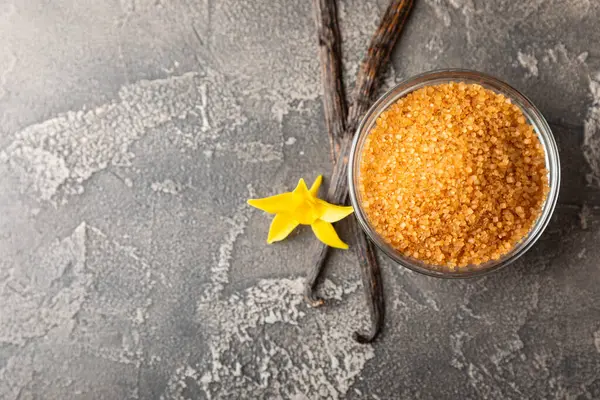 Aromatik vanilya şekeri. Vanilya kabukları. Vanilya çubukları, esmer ve beyaz şeker dokulu arka planda bir kasede. Vanilya çiçekleri, baharatlar ve tatlı ve pişirme için bitkiler. Mesaj için yer var. Boşluğu kopyala