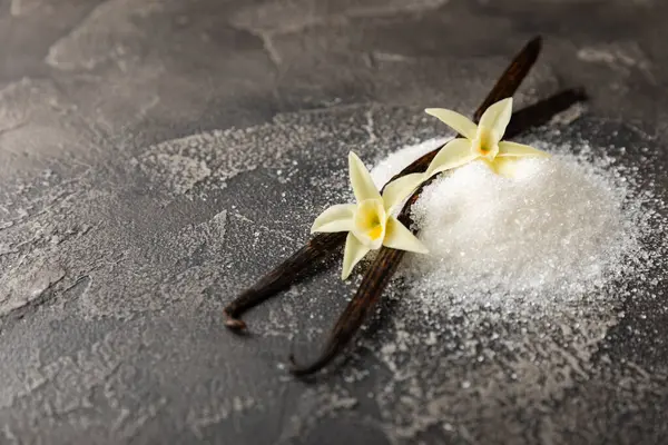 Aromatik vanilya şekeri. Vanilya kabukları. Vanilya çubukları, esmer ve beyaz şeker dokulu arka planda bir kasede. Vanilya çiçekleri, baharatlar ve tatlı ve pişirme için bitkiler. Mesaj için yer var. Boşluğu kopyala