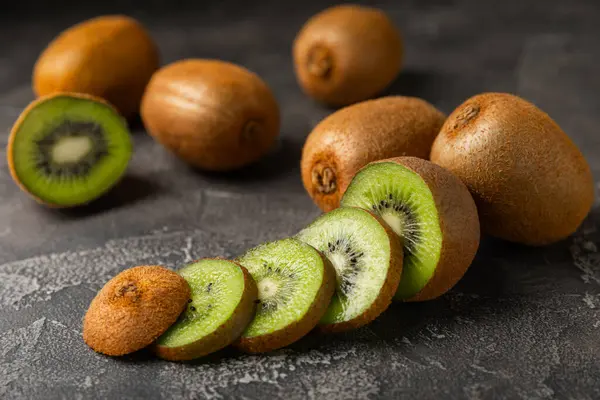 Ahşap arka planda Kivi. Masada tam meyve ve dilimler halinde yeşil kivi var. Taze sulu kivi. Tropik meyve. Organik meyve. Sağlıklı beslenme. Mesaj için yer var. Boşluğu kopyala