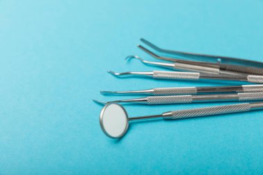 Mavi arkaplandaki dişçi aletleri. Diş hekimi konsepti. Diş bakımı, diş sağlığı konsepti. Ağız boşluğuna dikkat etmek anlamına geliyor. Diş modeli ve dişçi aletleri. Diş hijyeni. Mesaj için yer var. Boşluğu kopyala.