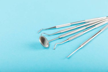 Mavi arkaplandaki dişçi aletleri. Diş hekimi konsepti. Diş bakımı, diş sağlığı konsepti. Ağız boşluğuna dikkat etmek anlamına geliyor. Diş modeli ve dişçi aletleri. Diş hijyeni. Mesaj için yer var. Boşluğu kopyala.