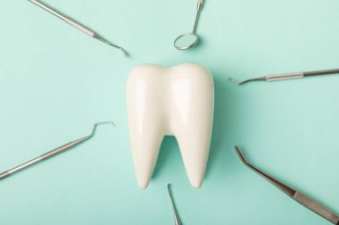 Mavi arkaplandaki dişçi aletleri. Diş hekimi konsepti. Diş bakımı, diş sağlığı konsepti. Ağız boşluğuna dikkat etmek anlamına geliyor. Diş modeli ve dişçi aletleri. Diş hijyeni. Mesaj için yer var. Boşluğu kopyala.