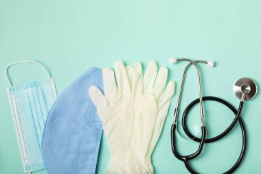 Tıbbi nitril eldivenler, mavi başlık, desenli arka planda tek kullanımlık tıbbi maske. Tıbbi koruyucu giysi. Cerrahi lateks eldivenler. Lastik eldiven üretimi. Tıp konsepti. Üst Manzara. Metni kopyala