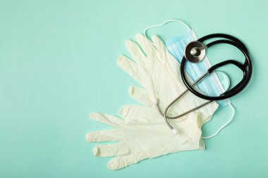 Tıbbi nitril eldivenler, mavi başlık, desenli arka planda tek kullanımlık tıbbi maske. Tıbbi koruyucu giysi. Cerrahi lateks eldivenler. Lastik eldiven üretimi. Tıp konsepti. Üst Manzara. Metni kopyala