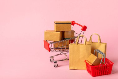 Çevrimiçi alışveriş kavramı. Karton kutu ve parlak renkli bir arka planda tramvayda alışveriş poşetleri. Alışveriş sepeti. İnternetten bilgisayar, tablet, telefon ve kredi kartı kullanarak alışveriş. Eve teslim.