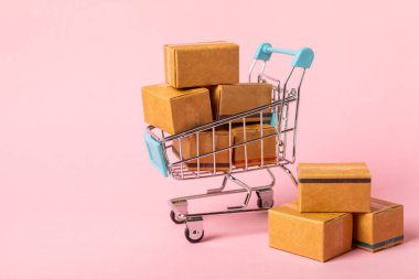 Çevrimiçi alışveriş kavramı. Karton kutu ve parlak renkli bir arka planda tramvayda alışveriş poşetleri. Alışveriş sepeti. İnternetten bilgisayar, tablet, telefon ve kredi kartı kullanarak alışveriş. Eve teslim.