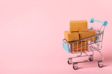 Çevrimiçi alışveriş kavramı. Karton kutu ve parlak renkli bir arka planda tramvayda alışveriş poşetleri. Alışveriş sepeti. İnternetten bilgisayar, tablet, telefon ve kredi kartı kullanarak alışveriş. Eve teslim.