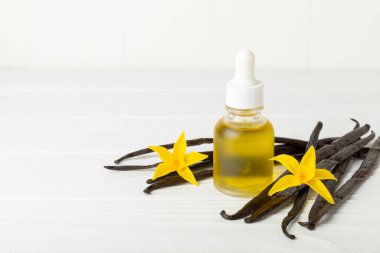 Bir şişe vanilya yağı ve desenli arka planda vanilya çiçeği. aromatik vanilyalı fasulye. Vanilya özü. Spa konsepti. Güzellik ve özen. Mesaj için yer. Boşluğu kopyala.