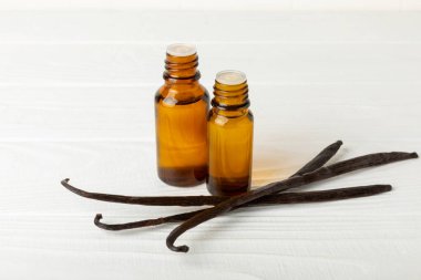 Bir şişe vanilya yağı ve desenli arka planda vanilya çiçeği. aromatik vanilyalı fasulye. Vanilya özü. Spa konsepti. Güzellik ve özen. Mesaj için yer. Boşluğu kopyala.