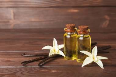 Bir şişe vanilya yağı ve desenli arka planda vanilya çiçeği. aromatik vanilyalı fasulye. Vanilya özü. Spa konsepti. Güzellik ve özen. Mesaj için yer. Boşluğu kopyala.