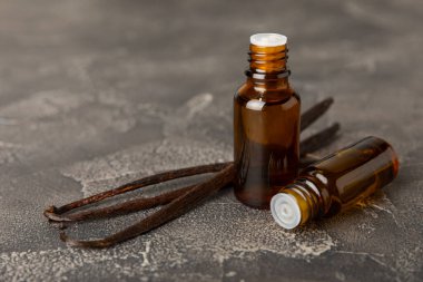 Bir şişe vanilya yağı ve desenli arka planda vanilya çiçeği. aromatik vanilyalı fasulye. Vanilya özü. Spa konsepti. Güzellik ve özen. Mesaj için yer. Boşluğu kopyala.