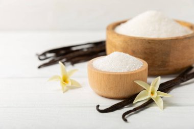 Aromatik vanilya şekeri. Vanilya kabukları. Vanilya çubukları, esmer ve beyaz şeker dokulu arka planda bir kasede. Vanilya çiçekleri, baharatlar ve tatlı ve pişirme için bitkiler. Mesaj için yer var. Boşluğu kopyala