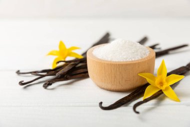 Aromatik vanilya şekeri. Vanilya kabukları. Vanilya çubukları, esmer ve beyaz şeker dokulu arka planda bir kasede. Vanilya çiçekleri, baharatlar ve tatlı ve pişirme için bitkiler. Mesaj için yer var. Boşluğu kopyala