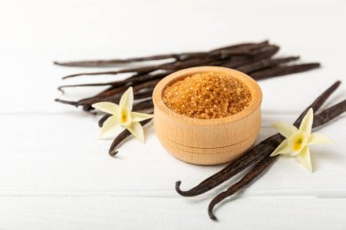 Aromatik vanilya şekeri. Vanilya kabukları. Vanilya çubukları, esmer ve beyaz şeker dokulu arka planda bir kasede. Vanilya çiçekleri, baharatlar ve tatlı ve pişirme için bitkiler. Mesaj için yer var. Boşluğu kopyala