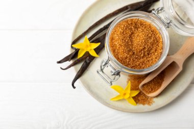 Aromatik vanilya şekeri. Vanilya kabukları. Vanilya çubukları, esmer ve beyaz şeker dokulu arka planda bir kasede. Vanilya çiçekleri, baharatlar ve tatlı ve pişirme için bitkiler. Mesaj için yer var. Boşluğu kopyala