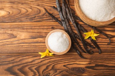 Aromatik vanilya şekeri. Vanilya kabukları. Vanilya çubukları, esmer ve beyaz şeker dokulu arka planda bir kasede. Vanilya çiçekleri, baharatlar ve tatlı ve pişirme için bitkiler. Mesaj için yer var. Boşluğu kopyala