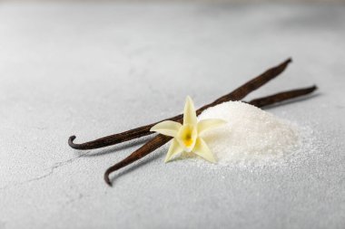 Aromatik vanilya şekeri. Vanilya kabukları. Vanilya çubukları, esmer ve beyaz şeker dokulu arka planda bir kasede. Vanilya çiçekleri, baharatlar ve tatlı ve pişirme için bitkiler. Mesaj için yer var. Boşluğu kopyala