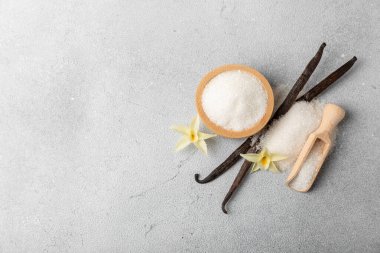 Aromatik vanilya şekeri. Vanilya kabukları. Vanilya çubukları, esmer ve beyaz şeker dokulu arka planda bir kasede. Vanilya çiçekleri, baharatlar ve tatlı ve pişirme için bitkiler. Mesaj için yer var. Boşluğu kopyala