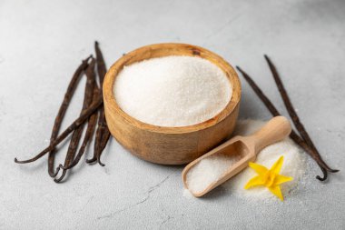 Aromatik vanilya şekeri. Vanilya kabukları. Vanilya çubukları, esmer ve beyaz şeker dokulu arka planda bir kasede. Vanilya çiçekleri, baharatlar ve tatlı ve pişirme için bitkiler. Mesaj için yer var. Boşluğu kopyala