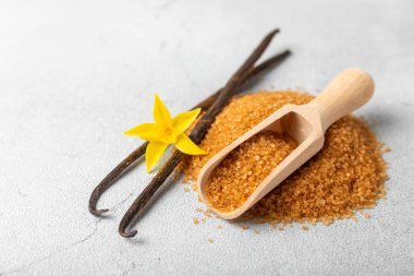 Aromatik vanilya şekeri. Vanilya kabukları. Vanilya çubukları, esmer ve beyaz şeker dokulu arka planda bir kasede. Vanilya çiçekleri, baharatlar ve tatlı ve pişirme için bitkiler. Mesaj için yer var. Boşluğu kopyala