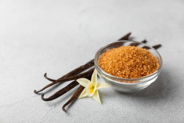Aromatik vanilya şekeri. Vanilya kabukları. Vanilya çubukları, esmer ve beyaz şeker dokulu arka planda bir kasede. Vanilya çiçekleri, baharatlar ve tatlı ve pişirme için bitkiler. Mesaj için yer var. Boşluğu kopyala