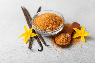 Aromatik vanilya şekeri. Vanilya kabukları. Vanilya çubukları, esmer ve beyaz şeker dokulu arka planda bir kasede. Vanilya çiçekleri, baharatlar ve tatlı ve pişirme için bitkiler. Mesaj için yer var. Boşluğu kopyala