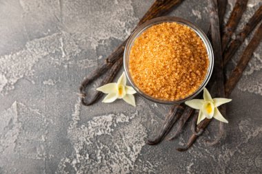 Aromatik vanilya şekeri. Vanilya kabukları. Vanilya çubukları, esmer ve beyaz şeker dokulu arka planda bir kasede. Vanilya çiçekleri, baharatlar ve tatlı ve pişirme için bitkiler. Mesaj için yer var. Boşluğu kopyala