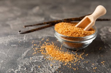 Aromatik vanilya şekeri. Vanilya kabukları. Vanilya çubukları, esmer ve beyaz şeker dokulu arka planda bir kasede. Vanilya çiçekleri, baharatlar ve tatlı ve pişirme için bitkiler. Mesaj için yer var. Boşluğu kopyala