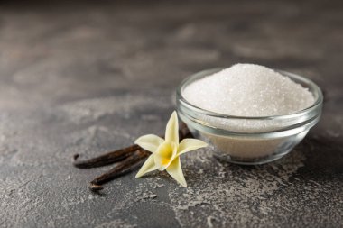 Aromatik vanilya şekeri. Vanilya kabukları. Vanilya çubukları, esmer ve beyaz şeker dokulu arka planda bir kasede. Vanilya çiçekleri, baharatlar ve tatlı ve pişirme için bitkiler. Mesaj için yer var. Boşluğu kopyala