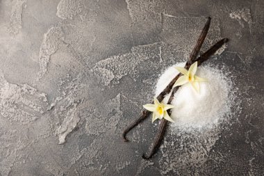 Aromatik vanilya şekeri. Vanilya kabukları. Vanilya çubukları, esmer ve beyaz şeker dokulu arka planda bir kasede. Vanilya çiçekleri, baharatlar ve tatlı ve pişirme için bitkiler. Mesaj için yer var. Boşluğu kopyala