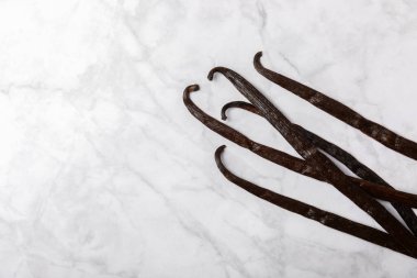 Dokulu bir arka planda vanilya kabukları. Vanilya çiçekleri ve tohumlar. Vanilyalı fasulye. Hamur işleri ve tatlılar için baharatlı baharat. Baharat. Mesaj için yer var. Boşluğu Kopyala