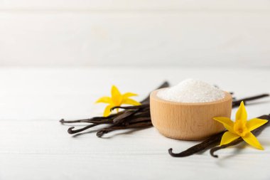 Aromatik vanilya şekeri. Vanilya kabukları. Vanilya çubukları, esmer ve beyaz şeker dokulu arka planda bir kasede. Vanilya çiçekleri, baharatlar ve tatlı ve pişirme için bitkiler. Mesaj için yer var. Boşluğu kopyala