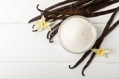 Aromatik vanilya şekeri. Vanilya kabukları. Vanilya çubukları, esmer ve beyaz şeker dokulu arka planda bir kasede. Vanilya çiçekleri, baharatlar ve tatlı ve pişirme için bitkiler. Mesaj için yer var. Boşluğu kopyala