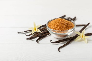 Aromatik vanilya şekeri. Vanilya kabukları. Vanilya çubukları, esmer ve beyaz şeker dokulu arka planda bir kasede. Vanilya çiçekleri, baharatlar ve tatlı ve pişirme için bitkiler. Mesaj için yer var. Boşluğu kopyala