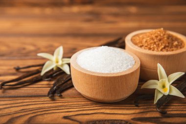 Aromatik vanilya şekeri. Vanilya kabukları. Vanilya çubukları, esmer ve beyaz şeker dokulu arka planda bir kasede. Vanilya çiçekleri, baharatlar ve tatlı ve pişirme için bitkiler. Mesaj için yer var. Boşluğu kopyala