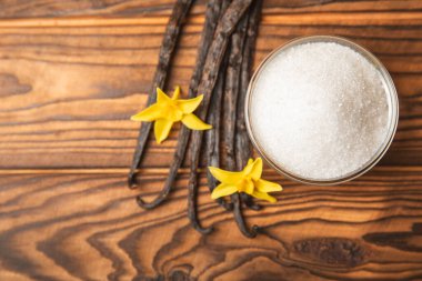 Aromatik vanilya şekeri. Vanilya kabukları. Vanilya çubukları, esmer ve beyaz şeker dokulu arka planda bir kasede. Vanilya çiçekleri, baharatlar ve tatlı ve pişirme için bitkiler. Mesaj için yer var. Boşluğu kopyala