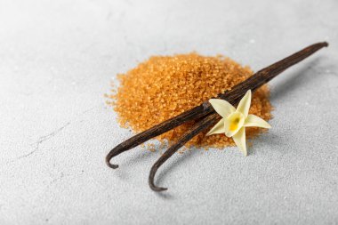 Aromatik vanilya şekeri. Vanilya kabukları. Vanilya çubukları, esmer ve beyaz şeker dokulu arka planda bir kasede. Vanilya çiçekleri, baharatlar ve tatlı ve pişirme için bitkiler. Mesaj için yer var. Boşluğu kopyala