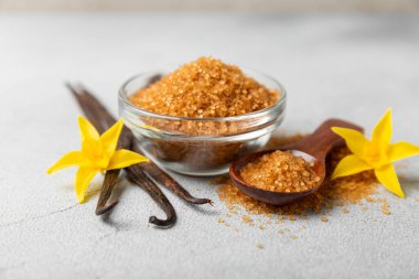 Aromatik vanilya şekeri. Vanilya kabukları. Vanilya çubukları, esmer ve beyaz şeker dokulu arka planda bir kasede. Vanilya çiçekleri, baharatlar ve tatlı ve pişirme için bitkiler. Mesaj için yer var. Boşluğu kopyala