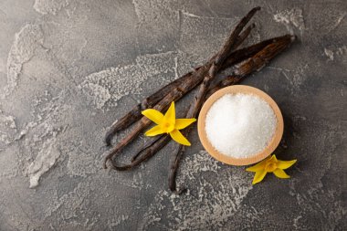 Aromatik vanilya şekeri. Vanilya kabukları. Vanilya çubukları, esmer ve beyaz şeker dokulu arka planda bir kasede. Vanilya çiçekleri, baharatlar ve tatlı ve pişirme için bitkiler. Mesaj için yer var. Boşluğu kopyala