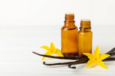 Bir şişe vanilya yağı ve desenli arka planda vanilya çiçeği. aromatik vanilyalı fasulye. Vanilya özü. Spa konsepti. Güzellik ve özen. Mesaj için yer. Boşluğu kopyala.