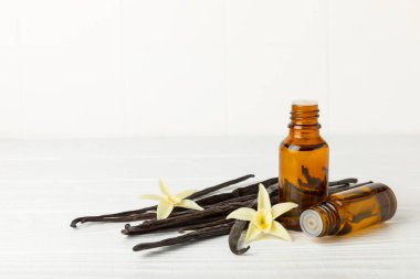 Bir şişe vanilya yağı ve desenli arka planda vanilya çiçeği. aromatik vanilyalı fasulye. Vanilya özü. Spa konsepti. Güzellik ve özen. Mesaj için yer. Boşluğu kopyala.