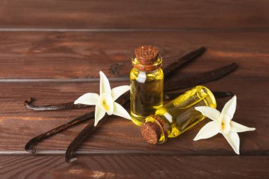 Bir şişe vanilya yağı ve desenli arka planda vanilya çiçeği. aromatik vanilyalı fasulye. Vanilya özü. Spa konsepti. Güzellik ve özen. Mesaj için yer. Boşluğu kopyala.