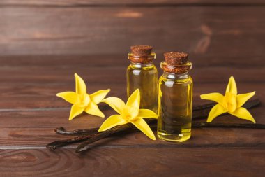 Bir şişe vanilya yağı ve desenli arka planda vanilya çiçeği. aromatik vanilyalı fasulye. Vanilya özü. Spa konsepti. Güzellik ve özen. Mesaj için yer. Boşluğu kopyala.