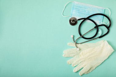Tıbbi nitril eldivenler, mavi başlık, desenli arka planda tek kullanımlık tıbbi maske. Tıbbi koruyucu giysi. Cerrahi lateks eldivenler. Lastik eldiven üretimi. Tıp konsepti. Üst Manzara. Metni kopyala
